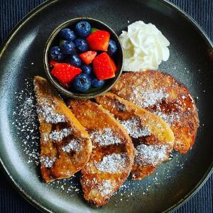 a plate of french toast with fruit and a bowl of whipped cream at Crafnant House - Bed & Breakfast in Trefriw