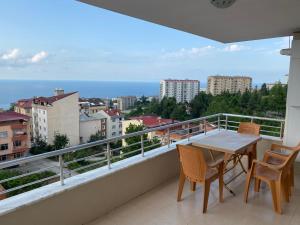 einen Balkon mit einem Tisch, Stühlen und Meerblick in der Unterkunft Ozgurcan Apart & Hotel in Trabzon