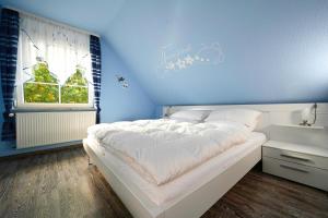 a bedroom with a white bed and a blue wall at Haus Johanna in Malchow