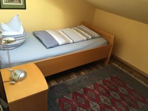 ein kleines Schlafzimmer mit einem Bett mit einer Lampe und einem Teppich in der Unterkunft Treibweg 41 in Husum