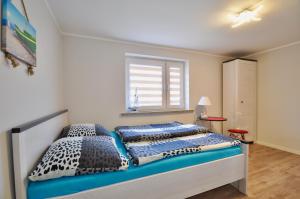 sypialnia z łóżkiem z niebieską pościelą i oknem w obiekcie Fala Dziwnow w Dziwnowie