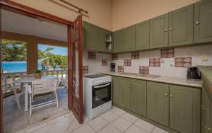 a kitchen with green cabinets and a table with a view of the ocean at Sea Elegance Villa in Zakynthos Town