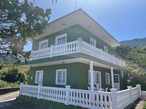 a green house with a white balcony on top at Casa Feluca in Breña Alta