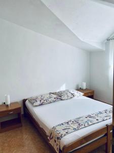 ein Schlafzimmer mit einem Bett mit zwei Nachttischen und zwei Tischen in der Unterkunft Apartmani Mima in Nečujam
