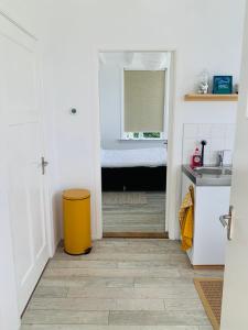 ein Badezimmer mit einem gelben Mülleimer und einem Waschbecken in der Unterkunft Studio49 in Ouddorp