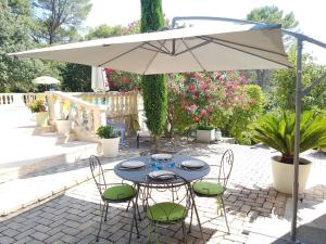 una mesa y sillas bajo una sombrilla en un patio en Le Mas des Hibiscus, en Trans-en-Provence
