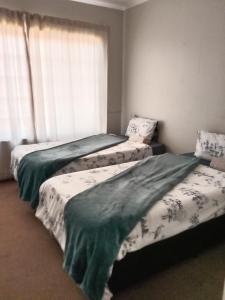 3 Betten in einem Zimmer mit Fenster in der Unterkunft Tumi's Home away- 3 Bedroom in Witbank