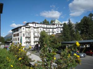 un gran edificio blanco con coches aparcados en un aparcamiento en Hotel Bären, en St. Moritz