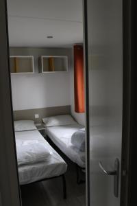 レ・マトゥにあるLes mobiles Homes de la Palmyreの鏡付きの小さな部屋のベッド2台