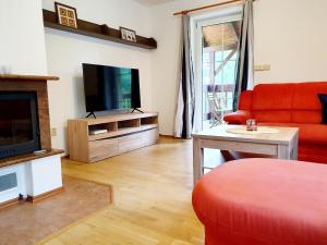 a living room with a red couch and a flat screen tv at Apartmány Srní u Hlinska in Hlinsko