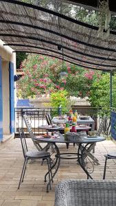 un patio al aire libre con mesas, sillas y flores en Le Mas des Hibiscus, en Trans-en-Provence