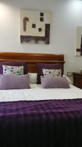 Una cama con sábanas y almohadas moradas. en Apartamento Camariñas, en Camariñas