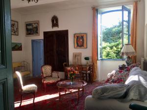 sala de estar con sofá, mesa y ventana en Les Asphodèles, en Saint-Hippolyte-du-Fort
