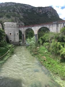 un puente sobre un río junto a una montaña en Les Asphodèles, en Saint-Hippolyte-du-Fort