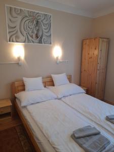 1 dormitorio con 1 cama blanca grande y 2 almohadas en Thermál Apartman Tiszafüred, en Tiszafüred