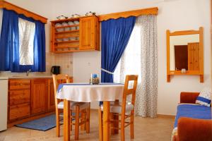 a kitchen with a table and some blue curtains at Petroula Apartments II in Emborios