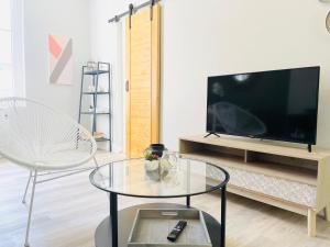 a living room with a tv and a glass table at Arina & Julien Dieppe in Dieppe