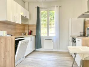 a kitchen with white cabinets and a window at Arina & Julien Dieppe in Dieppe