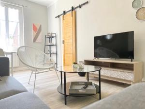 a living room with a tv and a couch and a table at Arina & Julien Dieppe in Dieppe