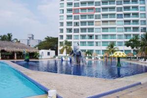 a swimming pool with a statue in front of a building at Costazul Suites 705 in Santa Marta