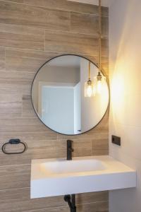 un bagno con specchio rotondo sopra un lavandino di Villa Valentina a Rales Altre 21 foto