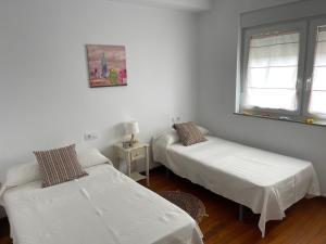a bedroom with two beds and a window at Apartamento Playa de Carnota in Carnota