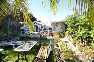 a patio with a table and a bench in a garden at Inés in Tijarafe