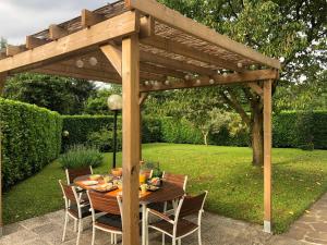 uma pérgola de madeira com uma mesa num jardim em In Giardino B&B em Cassina deʼ Pecchi