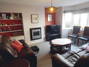 a living room with leather couches and a television at Luxurious 3 BR house for families, corporate stay with gardens and parking in Cambridge