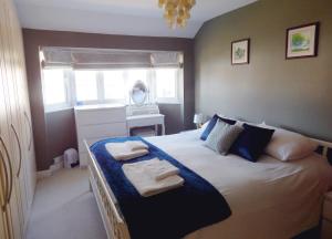 a bedroom with a large bed with towels on it at Luxurious 3 BR house for families, corporate stay with gardens and parking in Cambridge