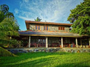 a stone house with blue windows and a green yard at Sarada lagoon view cabana in Hungama