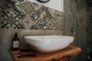 La salle de bains est pourvue d'un lavabo blanc sur une table en bois. dans l'établissement VENTITRÈ- House of Apulia Mea, à Alberobello