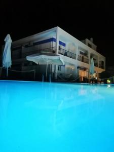 a large white building with a swimming pool at night at Villa Riviera in Stavros