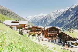 a group of wooden buildings on a hill with mountains at Andis Almdorf in Sölden