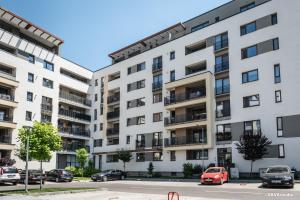 an apartment building with cars parked in a parking lot at Apartament Carpe Diem Brasov in Braşov