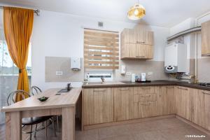 a kitchen with wooden cabinets and a wooden table at Apartament Carpe Diem Brasov in Braşov +9 photos