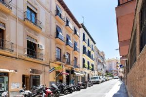 格拉纳达Apartamentos PROGRESO的停在建筑物旁边的街道上的一排摩托车