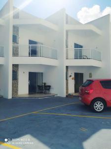 a red car parked in a parking lot in front of a building at Casa-2 Condomínio Elza em Arraial do Cabo in Arraial do Cabo