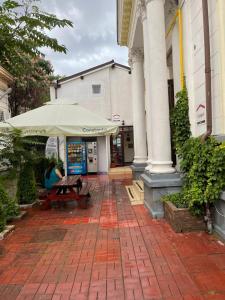 uma mesa de piquenique com um guarda-chuva em frente a um edifício em Piata Uniri Cozy Inn em Bucareste