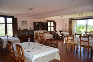 un restaurante con mesas y sillas blancas y ventanas en Masia Molí de Tartareu en Tartareu
