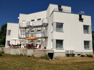 a white building with chairs and umbrellas in front of it at Laheveere Villa in Värska