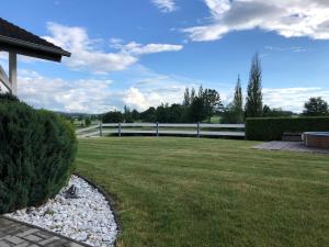 une cour herbeuse avec une clôture blanche et un champ dans l'établissement Holiday Home Bungalov Putim I, à Písek
