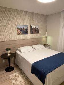 ein Schlafzimmer mit einem großen Bett und einem Tisch in der Unterkunft Melhor Apartamento centro Pomerode, perto de tudo in Pomerode