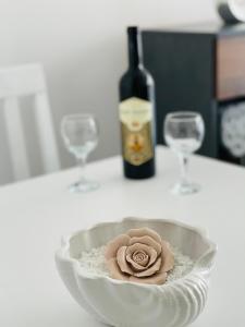 una ciotola con una rosa accanto a due bicchieri di vino di Apartmani Zivkovic Srebrno Jezero a Veliko Gradište