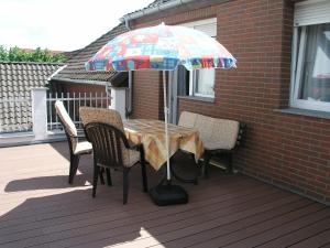 a table with chairs and an umbrella on a porch at Ferienwohnung am Deister mit großem Balkon in Springe