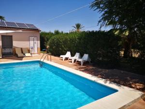 a swimming pool with chairs and a house at Casa los Jinetes in Carmona