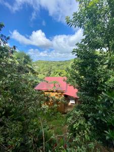 una casa con techo rojo en medio de árboles en Banana Cottage Ecolodge & Spa, en Le Gosier