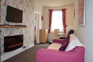 a living room with a pink couch and a fireplace at Ayrton House Holiday Apartments in Blackpool