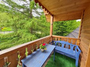 un portico con una panchina blu e dei fiori sopra di Brejowka a Krynica-Zdrój