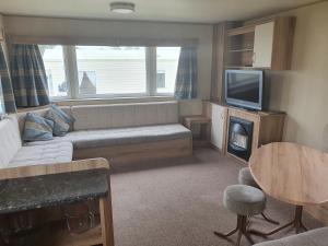 a living room with a couch and a tv at Haven Holiday Home Caister on Sea in Ormesby Saint Margaret